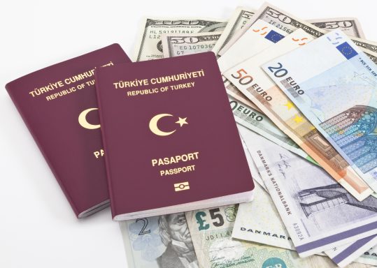 Zwei türkische Reisepässe liegen auf einem Stapel Bargeld und verschiedenen Währungen.
