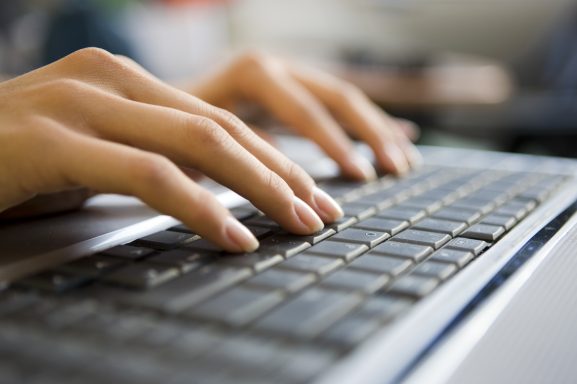 Hände tippen auf einer Computer-Tastatur.
