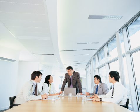 Besprechung im modernen Konferenzraum mit fünf Personen am Tisch.