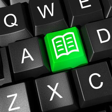 Grüne Taste mit offenem Buchsymbol auf einer Computer-Tastatur.