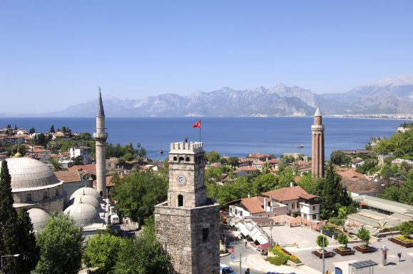 Blick auf die Küste mit historischen Gebäuden, Bergen und der Flagge der Türkei.