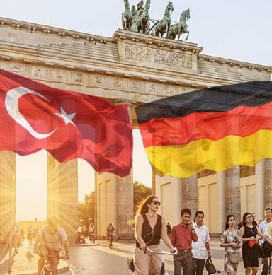 Menschen stehen vor dem Brandenburger Tor mit türkischer und deutscher Flagge.